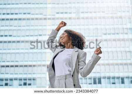 Happy excited confident professional young African American business woman office leader executive wearing suit celebrating financial goals standing in big city street feeling success and freedom. Royalty-Free Stock Photo #2343384077