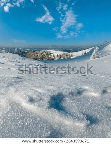 Winter calm mountain landscape with beautiful frosting trees and snowdrifts on slope. Composite image with considerable depth of field sharpness and macro snowflakes in the foreground.
