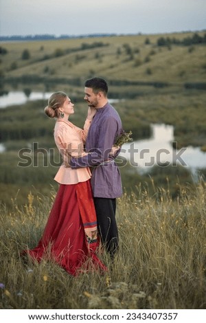 Photo of a couple in love in folk costumes near the lake.