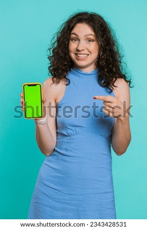 Young developer business woman holding smartphone with green screen chroma key mock up recommend good application promotional sale offer. Freelancer girl isolated on blue studio background. Vertical