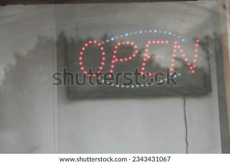 lit up open sign in capital letter caption writing text inside window with glare in front