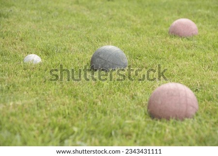 italian game bocce, old worn set of balls with one green and two red in shot screen right with the white ball screen left, close medium shot looking down on slight angle
