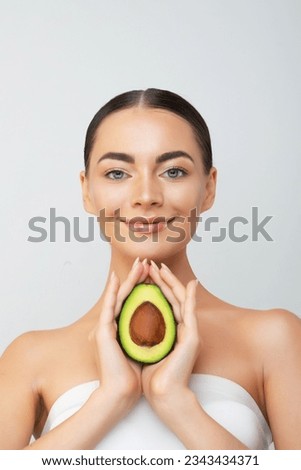 Beautiful young woman with fresh avocado on light background. High quality photo