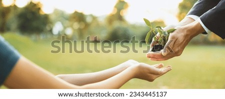 Panorama, businessman handing plant or sprout to young boy as eco company committed to corporate social responsible, reduce CO2 emission and embrace ESG principle for sustainable future.Gyre Royalty-Free Stock Photo #2343445137