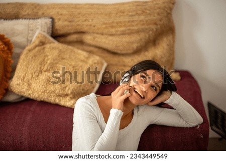 Portrait laughing young woman sitting at home with mobile phone