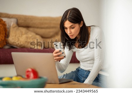 Portrait young woman sitting at home with laptop and mobile phone