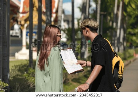 Young hipster traveller man and woman looking at city map during summer vacation in Thailand temple,  