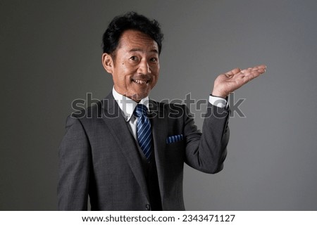 Asian middle aged businessman pointing side in black background