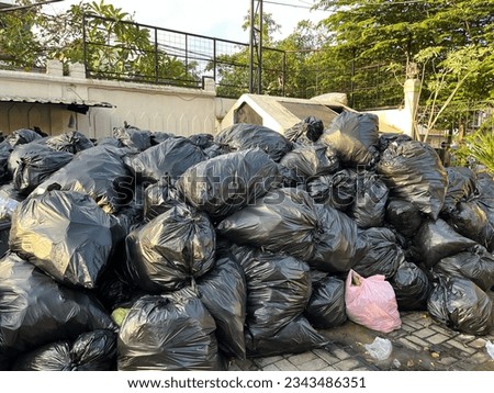Overloaded dumping ground with pile of black garbage bags on the street  Royalty-Free Stock Photo #2343486351