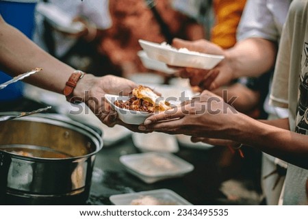 The help of volunteers helps to donate free food to the starving people. Royalty-Free Stock Photo #2343495535