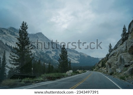 Tioga pass road with scenic view of massive granite rock formation on cloudy mystical day in Yosemite National Park, California, USA. Driving through forest and valleys. Roadtrip, freedom seeking Royalty-Free Stock Photo #2343497391
