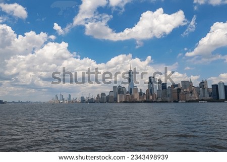 Captivating New York and New Jersey urban skyline with striking and modern skyscrapers reflecting on water seen from The Liberty Island. Think clouds above the city. Modern city. Royalty-Free Stock Photo #2343498939