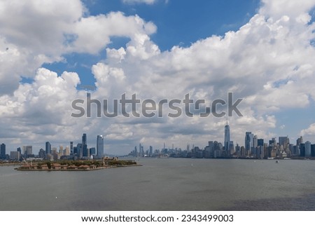 Captivating New York and New Jersey urban skyline with striking and modern skyscrapers reflecting on water seen from The Liberty Island. Think clouds above the city. Modern city.