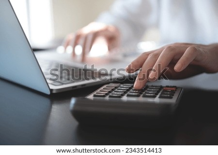 Close up of business woman accountant hand using calculator and laptop computer for calculating finance on desk office. business financial accounting concept Royalty-Free Stock Photo #2343514413