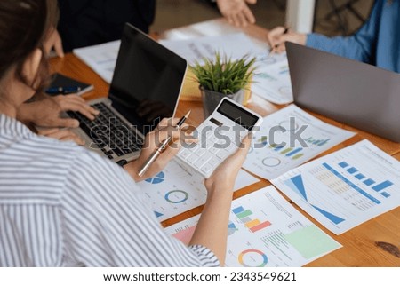 Businesswoman using a calculator to calculate numbers on a company's financial documents, she is analyzing historical financial data to plan how to grow the company. Financial concept. Royalty-Free Stock Photo #2343549621