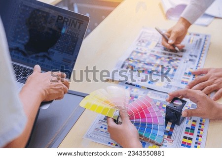 Crop image of worker checking print quality of media graphics proof print and color tone in printing industry. Selected focus Royalty-Free Stock Photo #2343550881