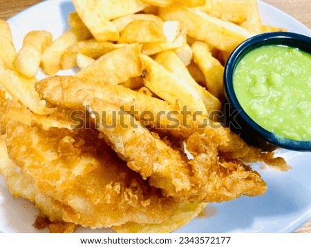 Chip shop style chips, battered fish served with mushy peas Royalty-Free Stock Photo #2343572177