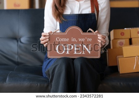 Store owner holding a sign opening the store. Shop that are open and welcome.