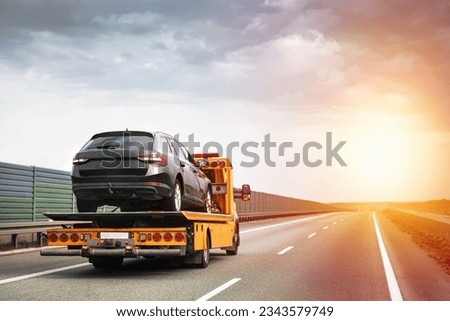 Reliable Towing and Recovery Services. Assistance for Vehicle Breakdowns and Accidents. Emergency roadside assistance on the highway. side view of the flatbed tow truck with a damaged vehicle Royalty-Free Stock Photo #2343579749