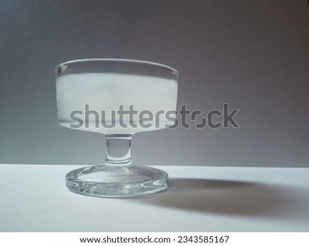 close-up of cold and fresh drink containing various natural ingredients, such as lime extract and cinnamon with ice cubes in a transparent glass on a white background