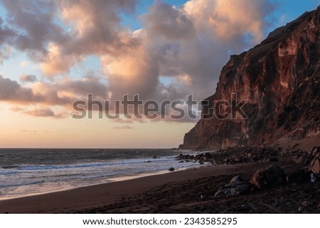 Scenic view during sunset on the volcanic sand beach Playa del Ingles in Valle Gran Rey, La Gomera, Canary Islands, Spain, Europe. Massive cliffs of the La Mercia range. Calm atmosphere at the seaside Royalty-Free Stock Photo #2343585295