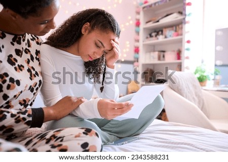 Mother Comforting Teenage Daughter In Bedroom Looking At Letter With Disappointing Exam Results Royalty-Free Stock Photo #2343588231