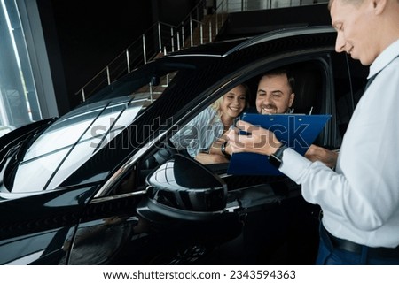 Happy caucasian couple signs a contract for the purchase of a car salon.