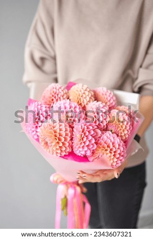 Mono bouquet of pink dahlias. Beautiful bouquet of flowers in womans hands. the work of the florist at a flower shop. Handsome fresh bouquet. Flowers delivery