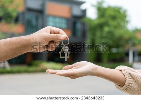 Woman buying or rent new home she holding key front of new house. Surprise happy young asian woman giving house key and smile to rent or purchase apartment home. Moving relocation concept. Royalty-Free Stock Photo #2343643233