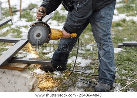 Close up of man grinding metal with circular grinder disc and electric sparks. Worker cutting metal with angle grinder for welding. Workers making fence with shielded metal arc welding