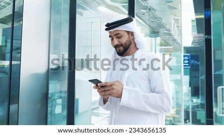 Arab Saudi, Emirati, Qatari, Omani Kuwaiti man inside a modern establishment with multiple floor storey ideal for shopping mall building lobby or airport Royalty-Free Stock Photo #2343656135