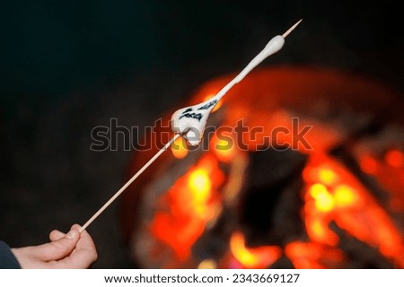 Marshmallows with Halloween pictures over fire. Funny leisure on traditional spooky holiday for children and families.