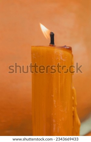 Close-up of burning candles with orange background