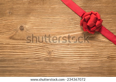 Decorative red ribbon and bow over wooden background 