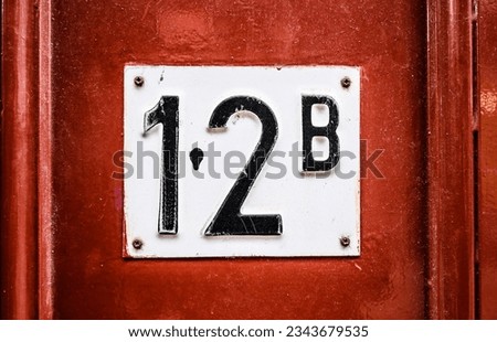Address sign on residential building wooden door with apartment number twelve. House identification signboard
