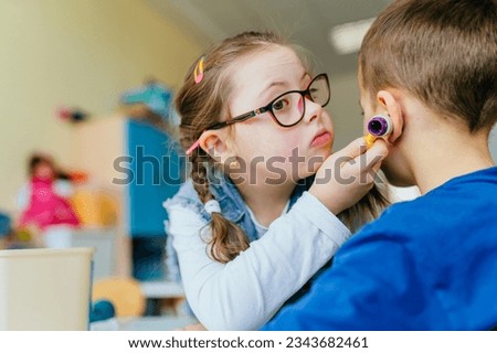 Cute little girl with Down syndrome playing doctor with sick unrecognizable boy as patient. Integration of children with special needs concept.