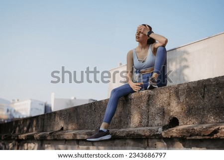 Young fitness woman resting after hard workout session on sunny morning. Royalty-Free Stock Photo #2343686797