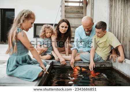 Cheerful family with three kids taking care of fish in pond.