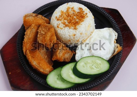 Photo of freshly cooked Filipino food called Bagnet or crispy deep fried pork belly served with rice and egg.