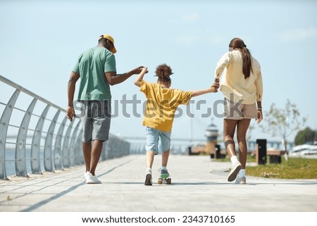 Little girl learning to skateboarding with her parents