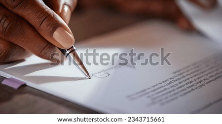 Close up of black hands of businesswoman signing agreement with ballpoint pen. African american hand of a mid adult woman signing a contract. Macro detail of woman signing agreement.  Royalty-Free Stock Photo #2343715661