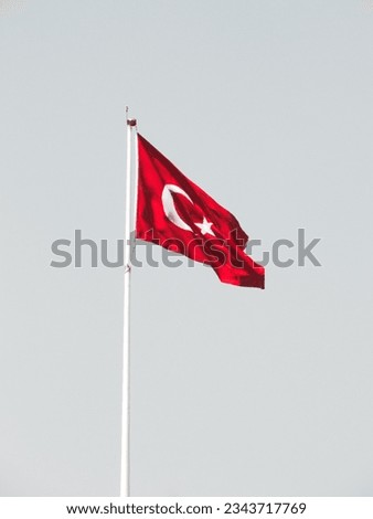 A red Turkish flag waving in the sky.