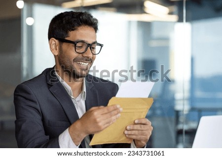 Young successful arab businessman at workplace inside office, man smiling satisfied received mail letter envelope notification message with good news, boss in business suit. Royalty-Free Stock Photo #2343731061