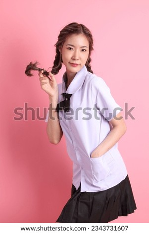 The Asian girl in Thai student uniform standing on the pink background.