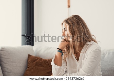 Side view young woman looking away at window sitting on couch at home. Frustrated confused female feels unhappy problem in personal life quarrel break up with boyfriend or unexpected pregnancy concept Royalty-Free Stock Photo #2343736261