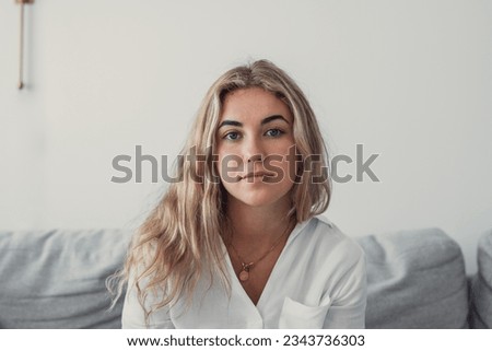 Positive serious millennial model girl home female head shot portrait. Beautiful young adult Caucasian woman looking at camera, posing in apartment. Front profile picture