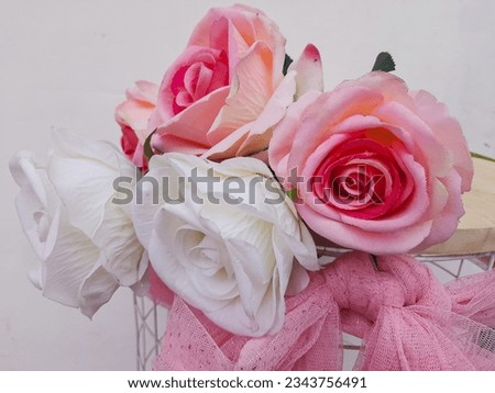 
A beautiful replica of a pink and white rose. home accessories, romantic. On a wooden table.
