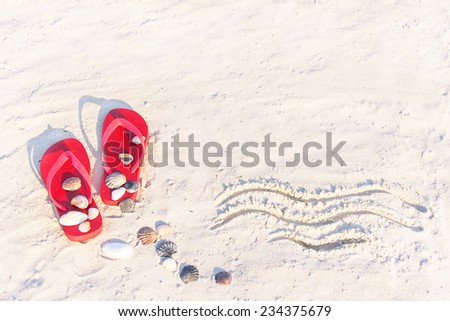 Sand texture (background) with flip flop sandals and shellfishes (scallop) on the beach. The wave drawing in the sand. The empty pattern for message. Summer vacations (travel) concept. Copy space. 