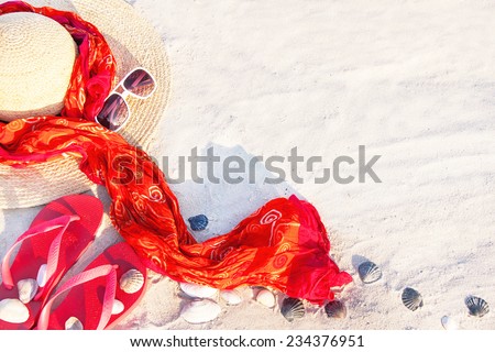 Sand texture (background) with flip flop sandals, hat, pareos (sarong), sunglasses, shellfishes (scallop) on the beach. The empty pattern for message. Summer vacations (travel) concept. Copy space. 