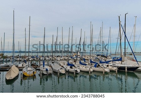 Wide-angle landscape view of anchored yachts in a harbor of yacht club in Lake Balaton, Balatonkenese. Stunning autumn landscape. Famous touristic place and romantic travel destination. Royalty-Free Stock Photo #2343788045
